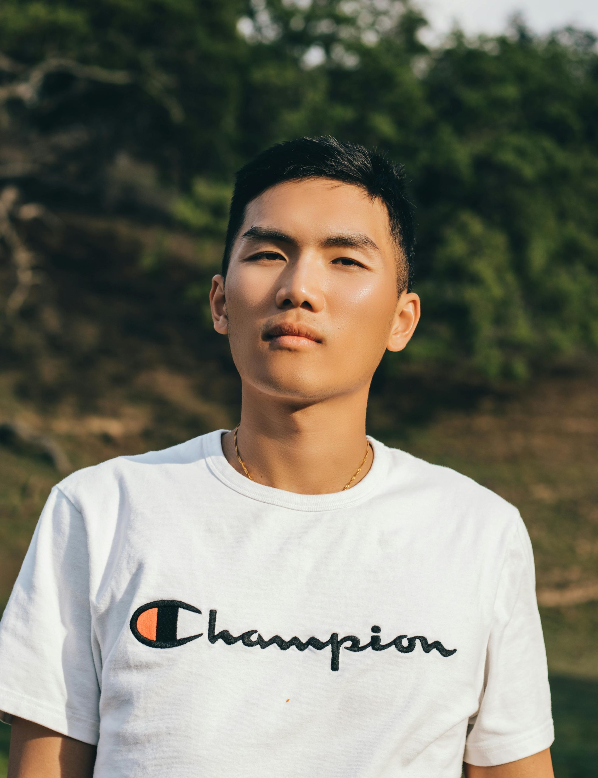 Young man posing outdoors in casual fashion with a relaxed expression.